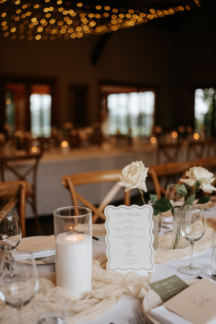 Decorated table with candles, flowers, and a menu card in a warmly lit room.