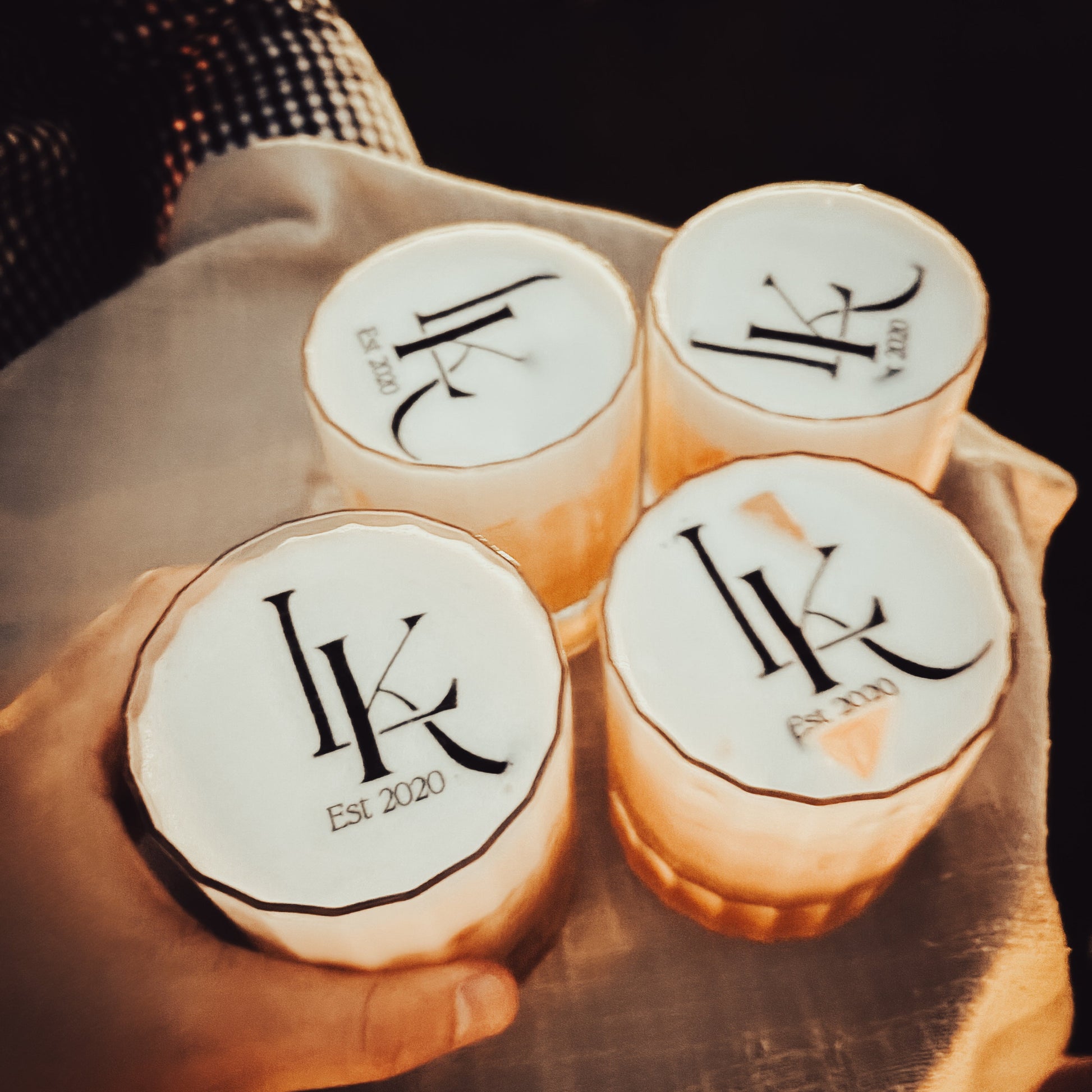 Four round containers with a logo and text on a wooden surface.